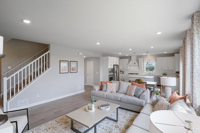 living room featuring light wood finished floors, stairway, visible vents, and recessed lighting