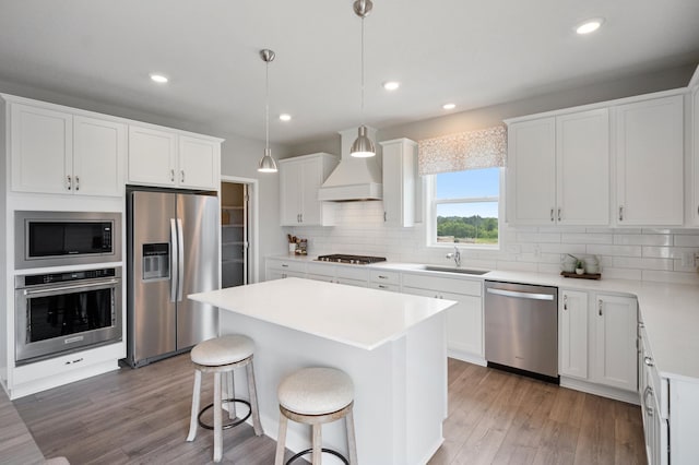 kitchen with stainless steel appliances, a sink, light wood-style flooring, and a center island