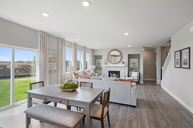 dining room featuring a glass covered fireplace, recessed lighting, wood finished floors, and baseboards