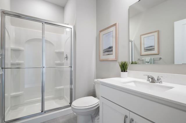 bathroom with toilet, a stall shower, and vanity