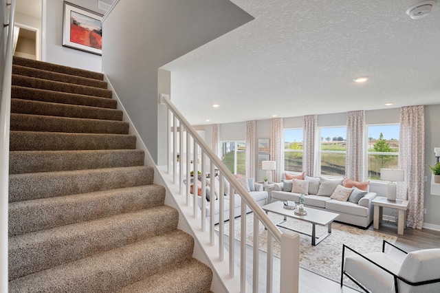 stairs with a textured ceiling, baseboards, wood finished floors, and recessed lighting