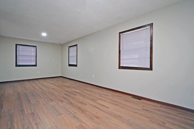 unfurnished room featuring light hardwood / wood-style floors and a textured ceiling