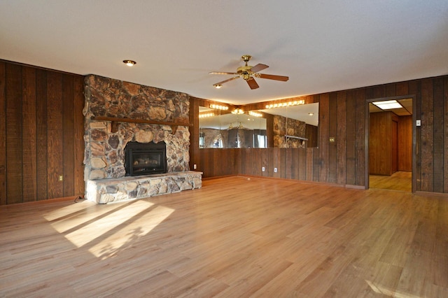 unfurnished living room with wooden walls, light wood-type flooring, and ceiling fan