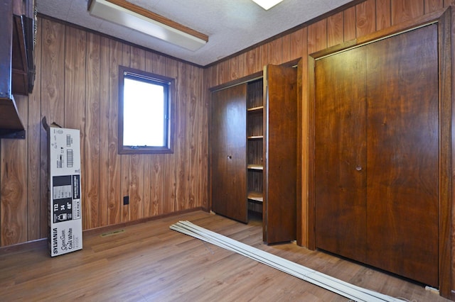 unfurnished bedroom with a closet, wood walls, and wood-type flooring