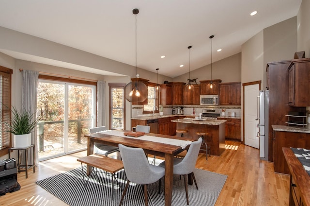 dining room featuring light hardwood / wood-style floors, sink, and high vaulted ceiling