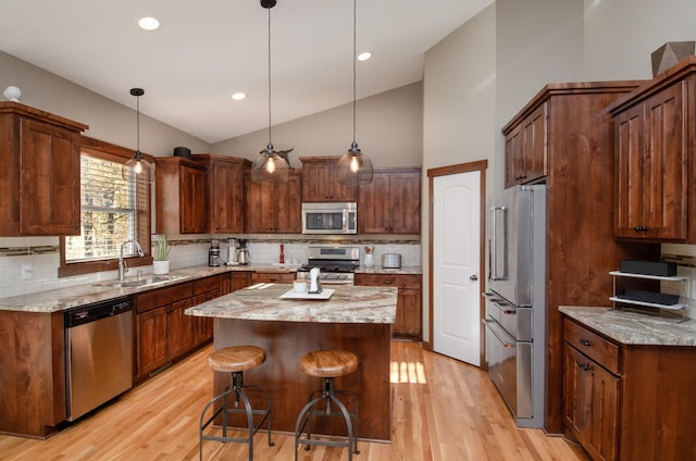 kitchen with stainless steel appliances, backsplash, lofted ceiling, a kitchen island, and sink