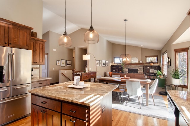 kitchen featuring pendant lighting, lofted ceiling, a kitchen island, light stone counters, and high end refrigerator