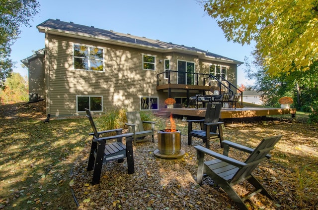 rear view of property with a wooden deck and a fire pit