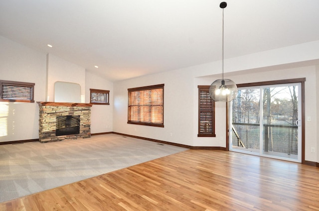 unfurnished living room featuring baseboards, lofted ceiling, wood finished floors, an inviting chandelier, and a fireplace