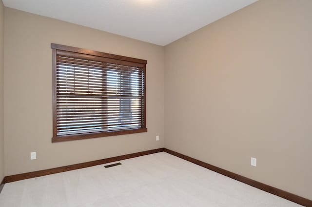 carpeted empty room featuring baseboards and visible vents