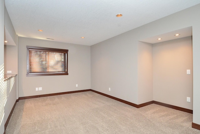 spare room featuring light carpet, baseboards, and recessed lighting