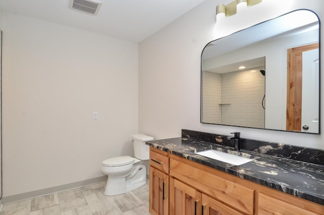 full bathroom featuring toilet, vanity, visible vents, baseboards, and a shower