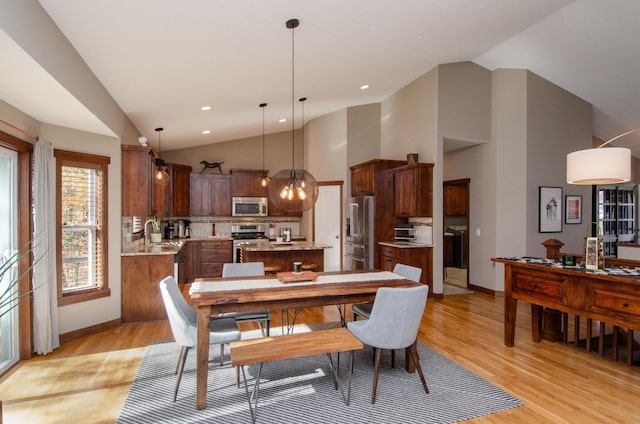 dining space featuring light wood finished floors, baseboards, high vaulted ceiling, and recessed lighting