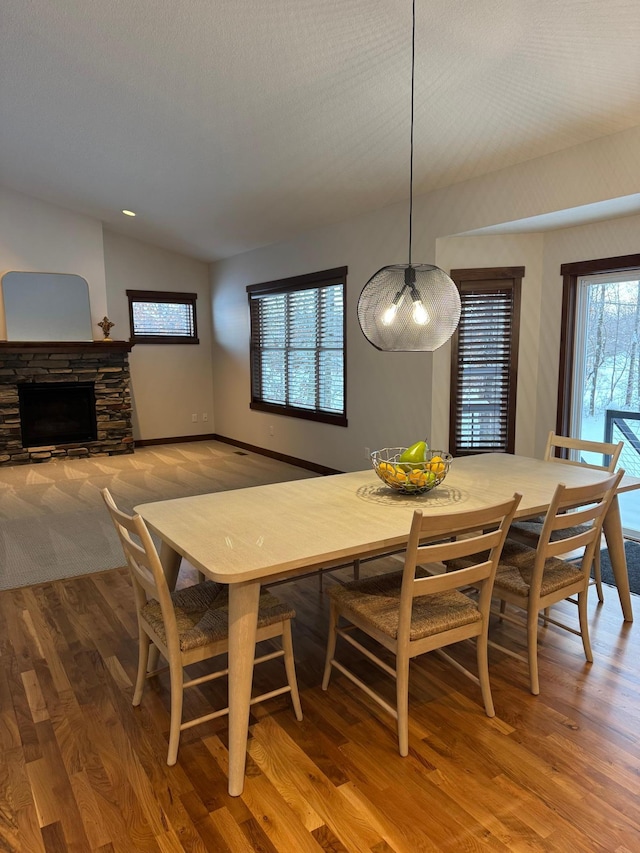 dining area featuring breakfast area, lofted ceiling, a fireplace, and wood finished floors