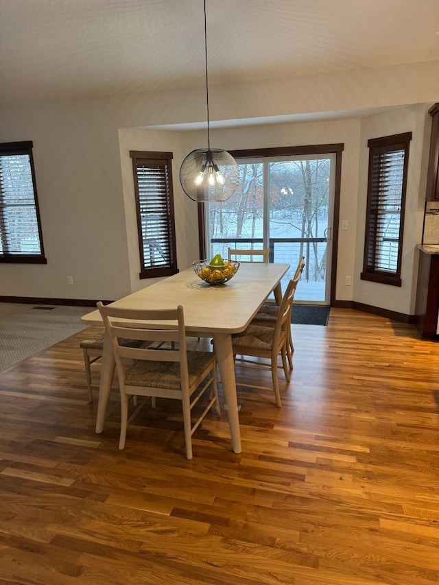 dining area featuring an inviting chandelier, baseboards, and wood finished floors