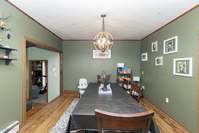 dining room with ornamental molding, a baseboard heating unit, a notable chandelier, and light wood-type flooring