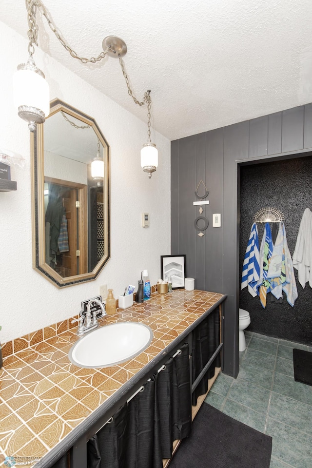 bathroom featuring toilet, a textured ceiling, and vanity