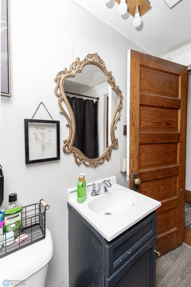 bathroom with vanity, a textured ceiling, wood-type flooring, and toilet