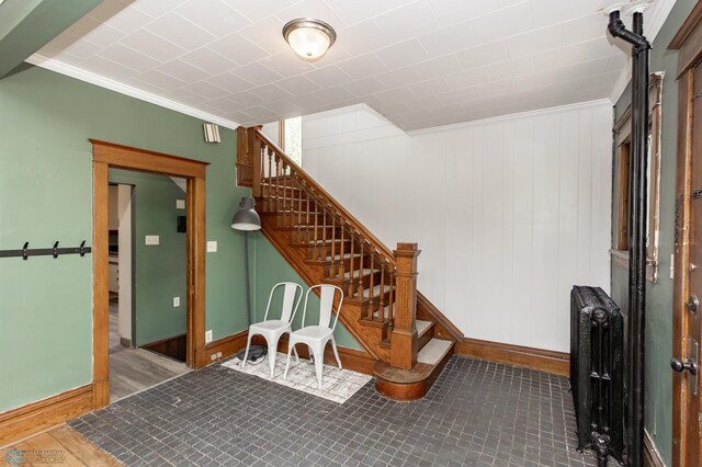 807 4th St S, Moorhead, MN 56560 - below grade area featuring crown molding, stairway, baseboards, radiator heating unit, and wood finished floors