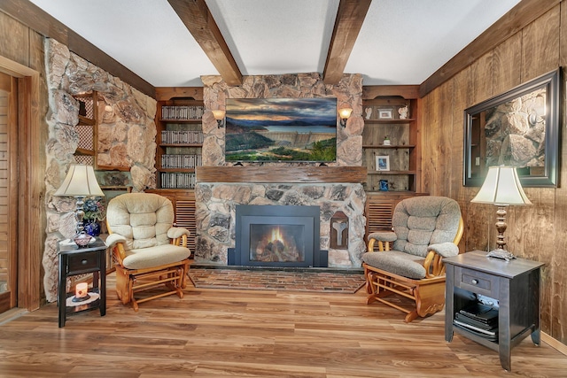 sitting room featuring wooden walls, beamed ceiling, and light hardwood / wood-style floors