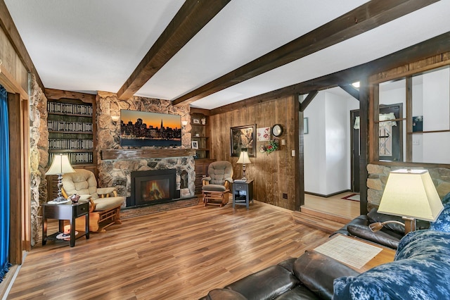 living room with a fireplace, beam ceiling, wood walls, and hardwood / wood-style flooring