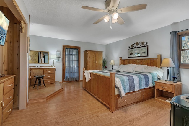 bedroom with ceiling fan, a textured ceiling, and light wood-type flooring