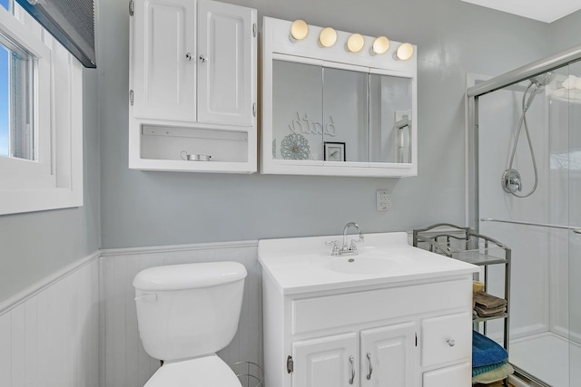 bathroom featuring vanity, toilet, and a shower with door