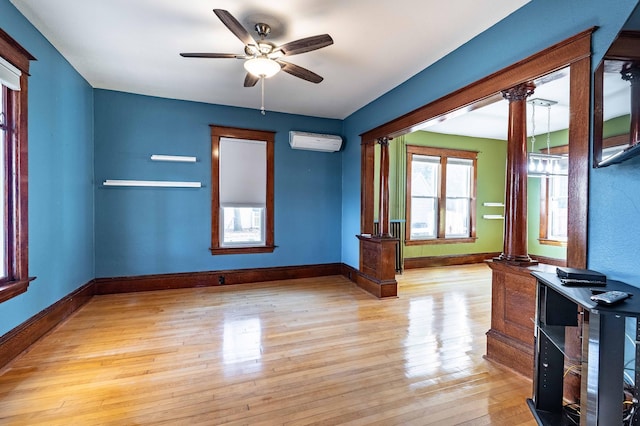 unfurnished room featuring ornate columns, ceiling fan, light hardwood / wood-style flooring, and a wall mounted air conditioner