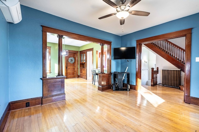 unfurnished living room featuring ceiling fan, an AC wall unit, light hardwood / wood-style flooring, and radiator heating unit