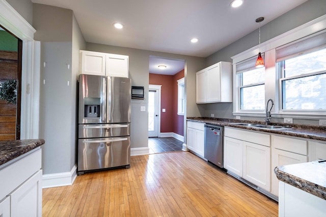 kitchen with appliances with stainless steel finishes, light hardwood / wood-style flooring, decorative light fixtures, and white cabinetry