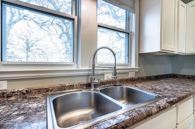 details featuring sink, white cabinetry, and dark stone counters