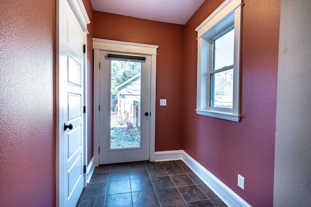 doorway to outside with dark tile patterned floors