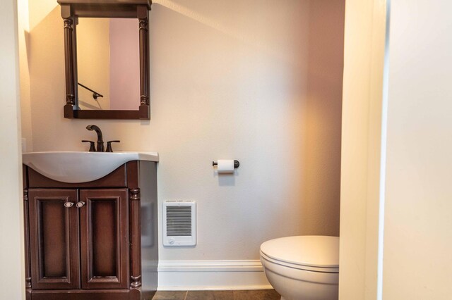 bathroom with toilet, vanity, heating unit, and tile patterned flooring