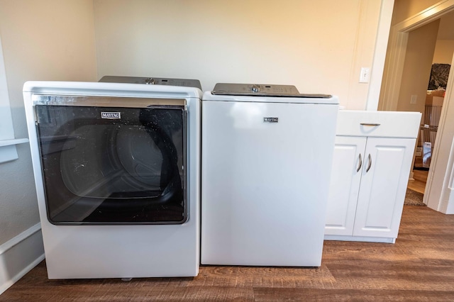 washroom featuring washer and clothes dryer, dark hardwood / wood-style floors, and cabinets