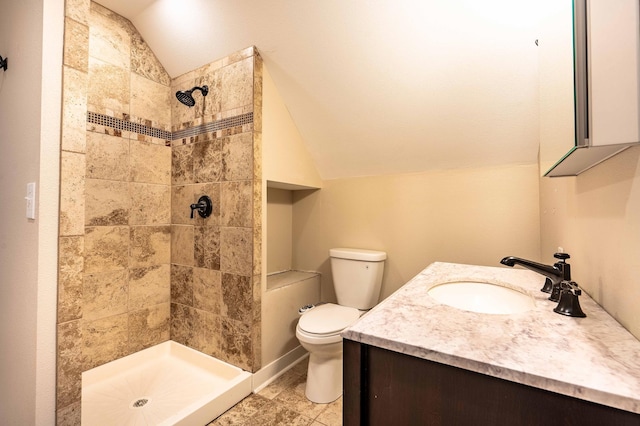 bathroom featuring vanity, toilet, vaulted ceiling, and a tile shower