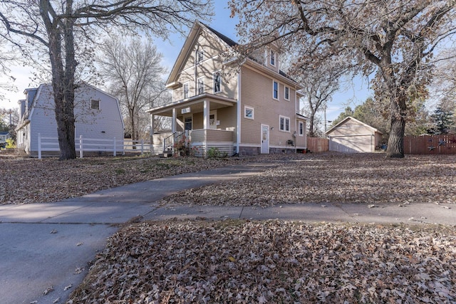 view of property exterior with a garage, a porch, and an outdoor structure