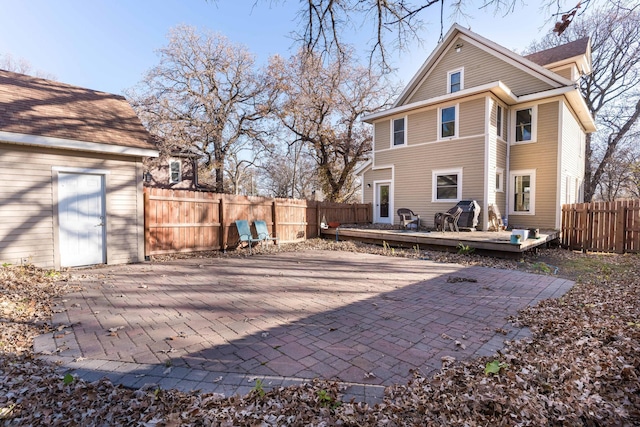 back of property with a wooden deck, a patio area, and a shed