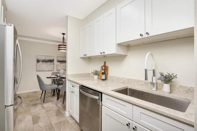 kitchen featuring light stone countertops, sink, appliances with stainless steel finishes, and pendant lighting