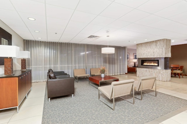 tiled living room with a large fireplace and a paneled ceiling