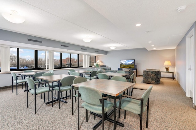 carpeted dining space featuring a textured ceiling and plenty of natural light