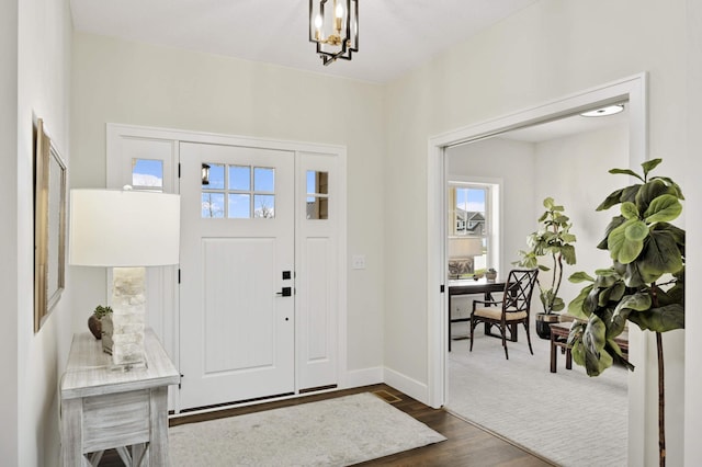 foyer entrance featuring a wealth of natural light, dark hardwood / wood-style floors, and a chandelier