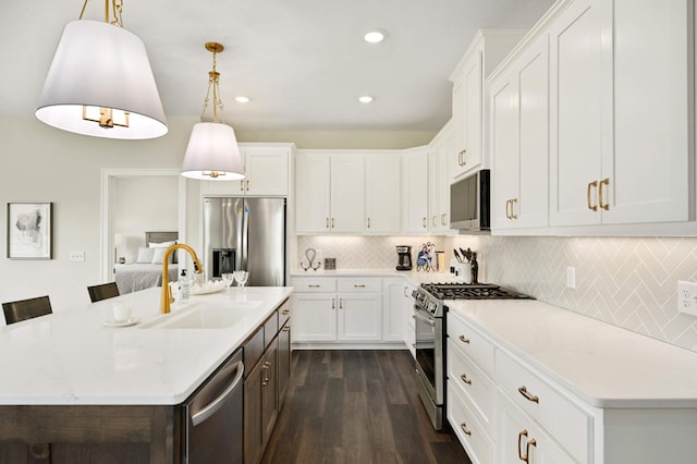 kitchen featuring a center island with sink, sink, decorative light fixtures, and appliances with stainless steel finishes