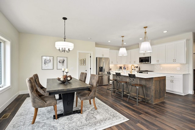 dining space with a wealth of natural light, dark hardwood / wood-style floors, and a chandelier