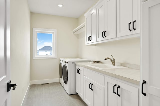 clothes washing area with cabinets, sink, and independent washer and dryer