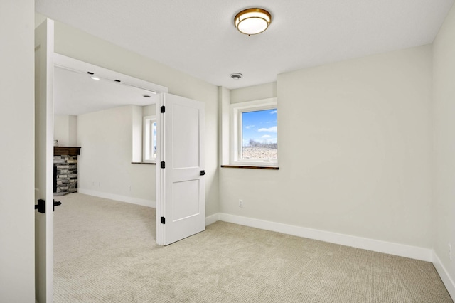 spare room with light carpet and a fireplace