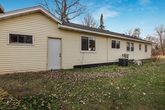 rear view of property with a lawn and central air condition unit