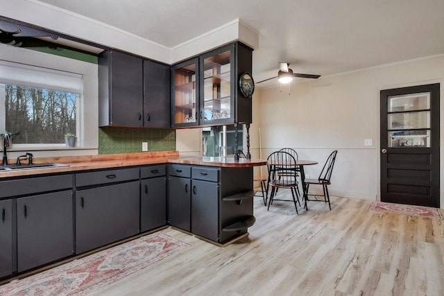 kitchen with sink, crown molding, light hardwood / wood-style floors, and backsplash