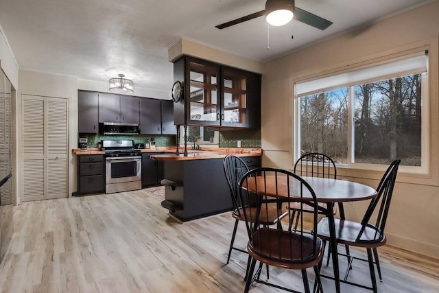 kitchen featuring wood counters, stainless steel gas stove, light hardwood / wood-style flooring, ceiling fan, and decorative backsplash