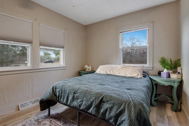 bedroom with multiple windows and hardwood / wood-style floors