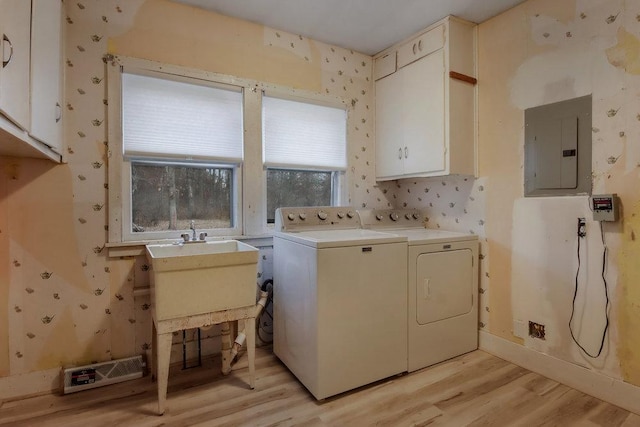 laundry area featuring sink, electric panel, cabinets, separate washer and dryer, and light wood-type flooring